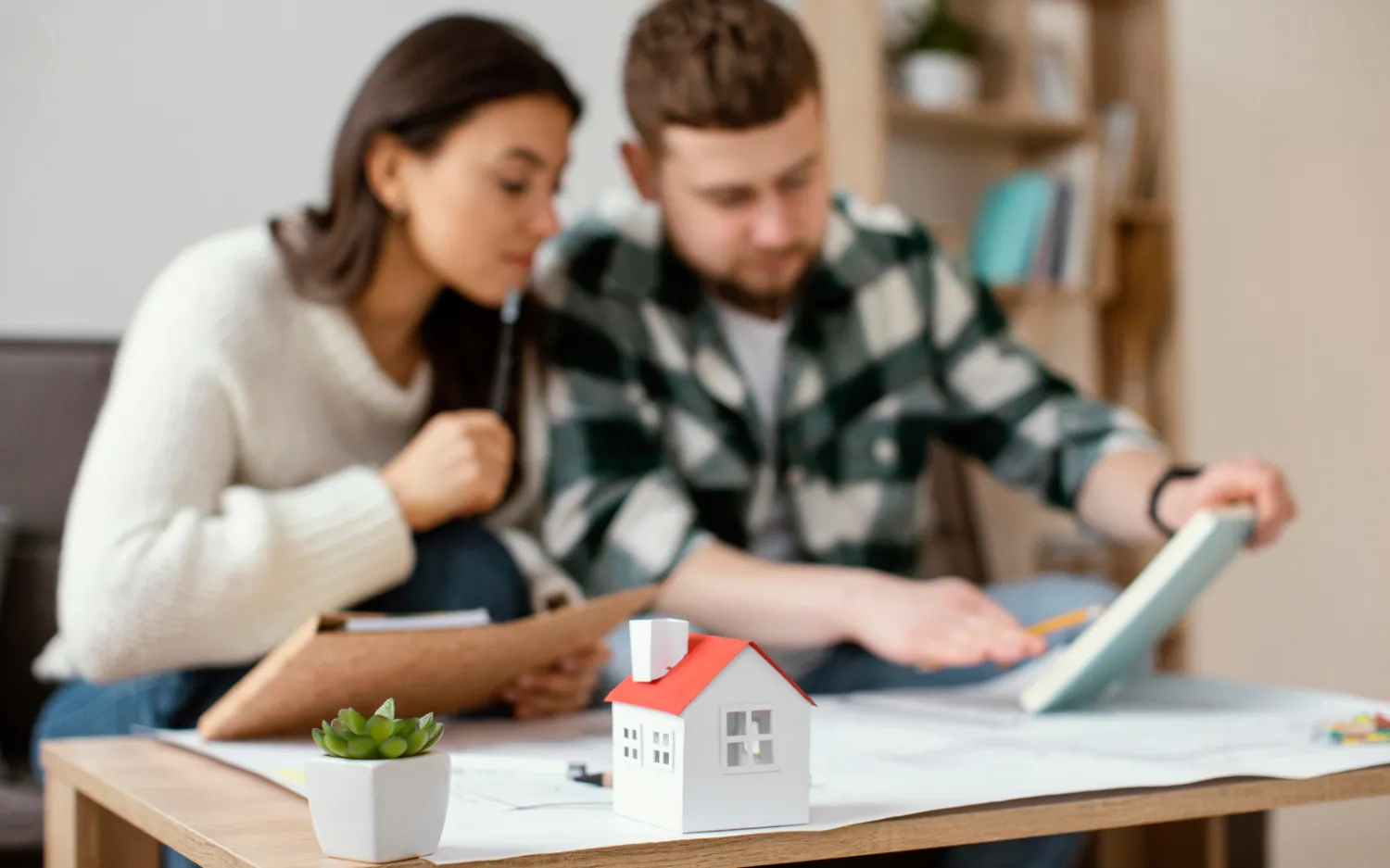 Modern workspace featuring wooden tables, green chairs, a vibrant wall, and a cozy seating area with cushions. Ideal for collaboration.